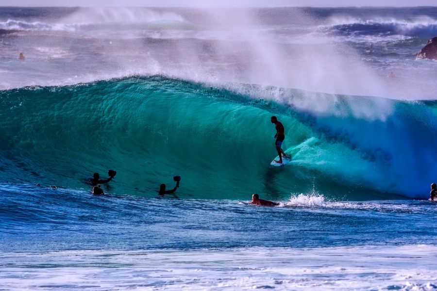 A group of surfers in the curl of wave.