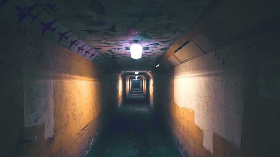 A long dark pedestrian tunnel with a few lights.