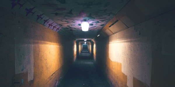 A long dark pedestrian tunnel with a few lights.