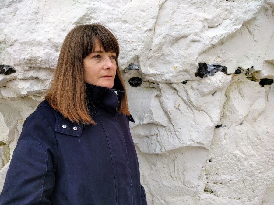 Portrait of journalist and writer Sophie Morris standing in front of a white chalk cliff.