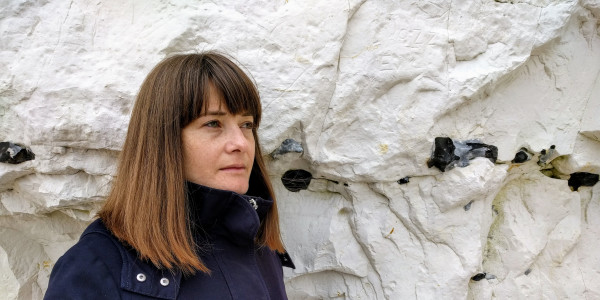 Portrait of journalist and writer Sophie Morris standing in front of a white chalk cliff.